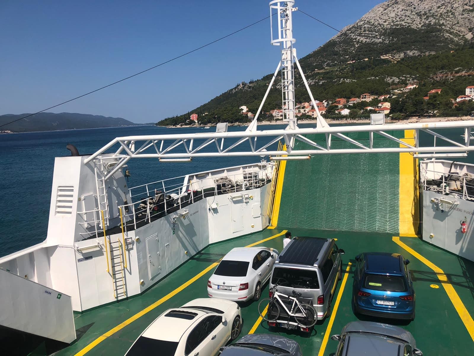 Cars on ferry deck crossing to Korčula with mountain views